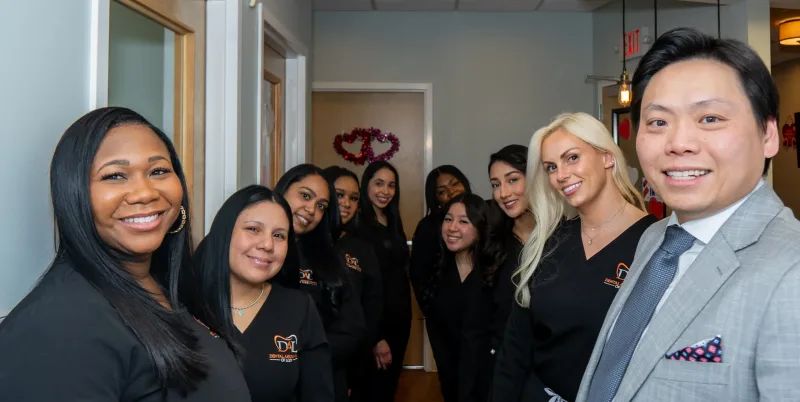A group of people in matching black uniforms smile in a hallway.