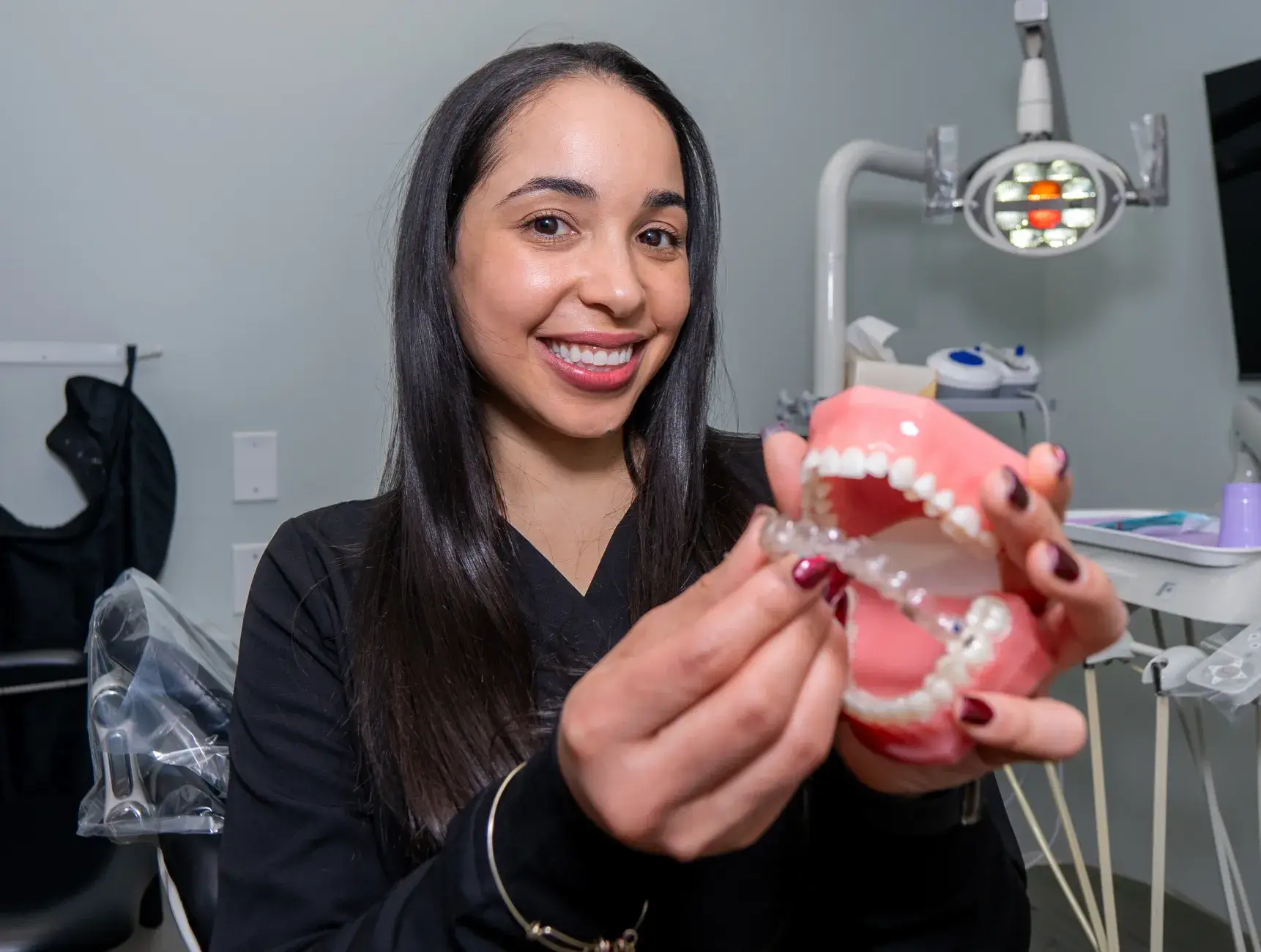 A dentist holds a dental model, demonstrating how to fit a dental appliance.