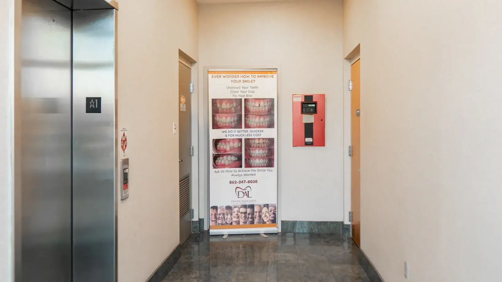 Elevator lobby with a dental advertisement banner showing teeth images and contact information.