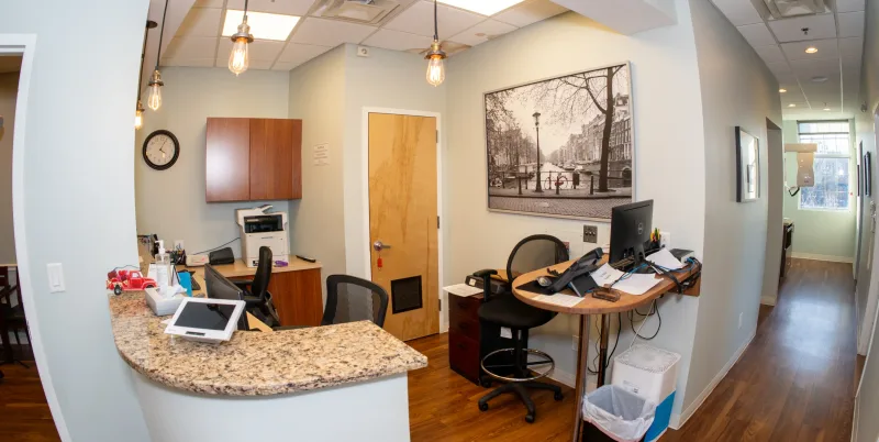 A small reception area with a curved granite desk, computer and chairs.