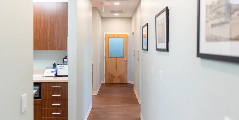 A hallway in an office with framed pictures on the wall.